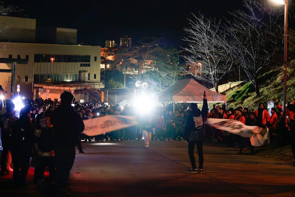夜のまつりの会場で旗を掲げる参加者